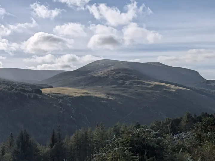 A mountain ridge and valley under a partly cloudy sky.